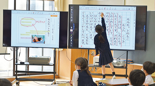 電子黒板に映し出された例文のポイントに赤線を入れる児童（1年・国語）