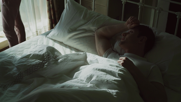 カラーグレーディングの比較画像 窓から日が差したベッドに男性が寝ている、寝具の白さが目立っている