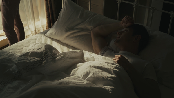 カラーグレーディングの比較画像 窓から日が差したベッドに男性が寝ている、アンバーの調整により夕方であることが伝わりやすい